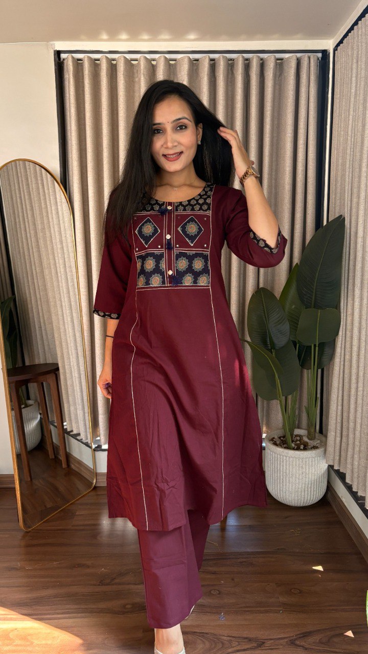 Woman wearing a maroon cotton kurti and pant set with Ajrakh print details, smiling at the camera.