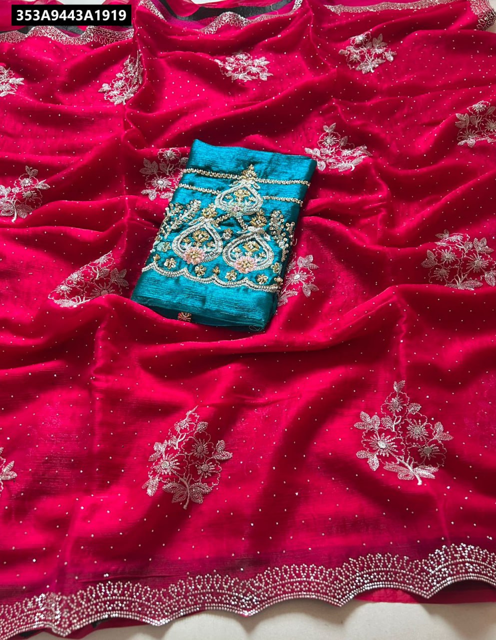 Flat lay of fuchsia crunchy chiffon crush silk saree with silver embroidery and teal embroidered blouse