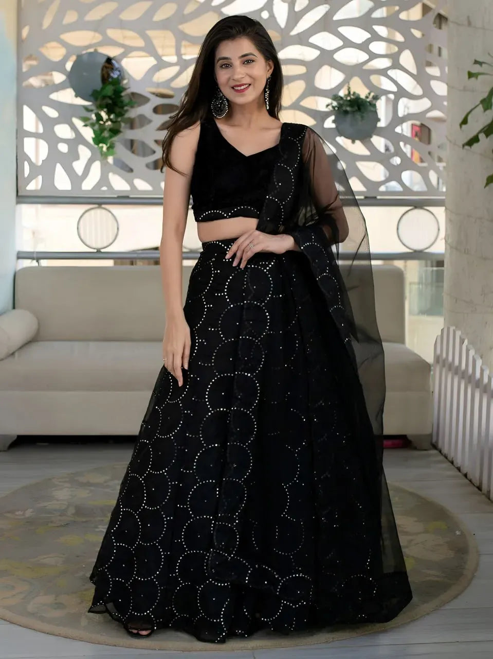 Model posing in black sequin lehenga choli with sheer dupatta facing front
