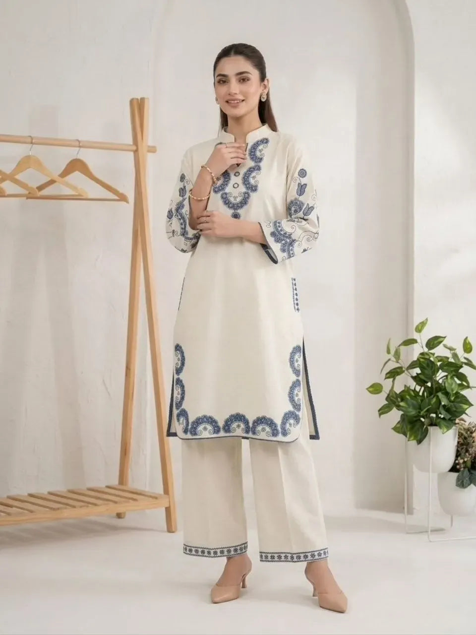 Model wearing off-white and blue embroidered cotton co-ord set standing in a minimalist room