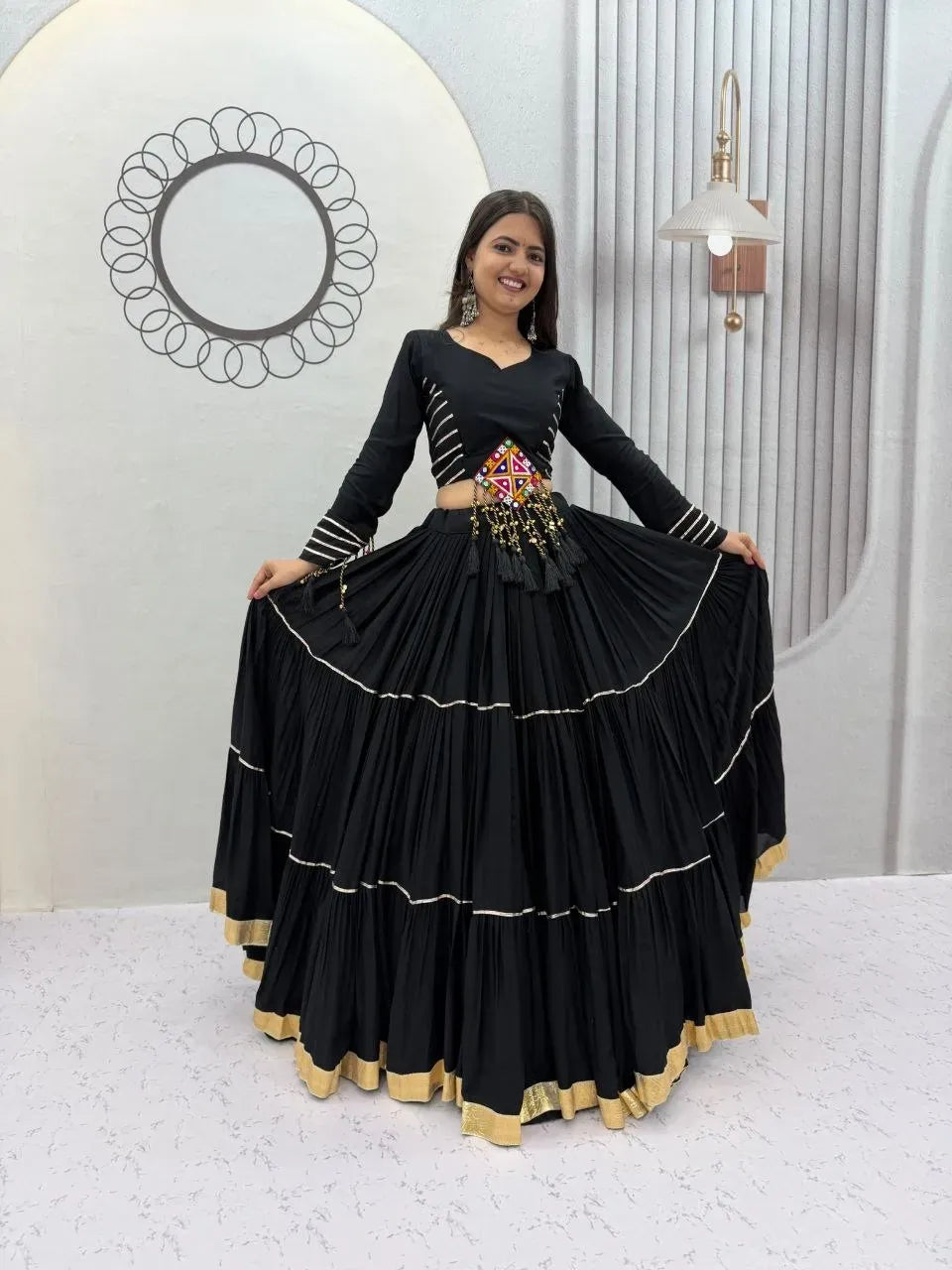 Front facing view of model wearing black cotton lehenga choli with heavy flare and traditional belt detail