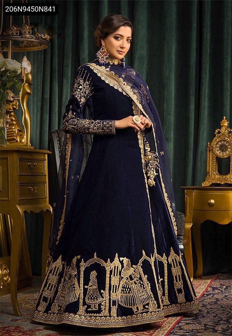 Full body shot of a woman modeling the navy blue velvet embroidered Anarkali gown, looking elegant.