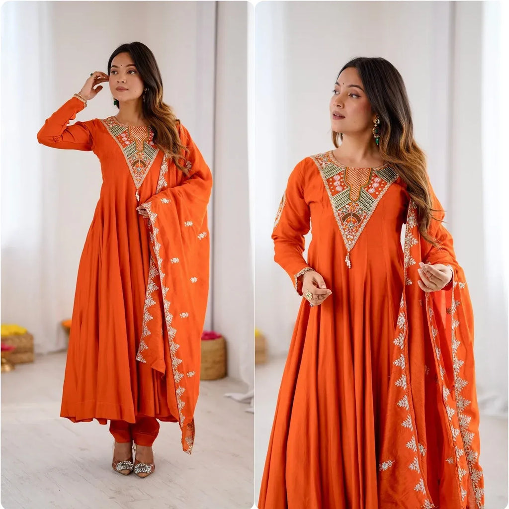 Model wearing orange embroidered anarkali suit with dupatta holding pose
