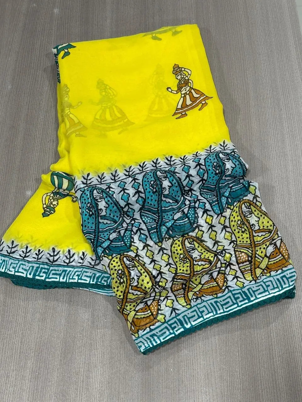 Folded yellow saree with folk art motifs and teal patterned border