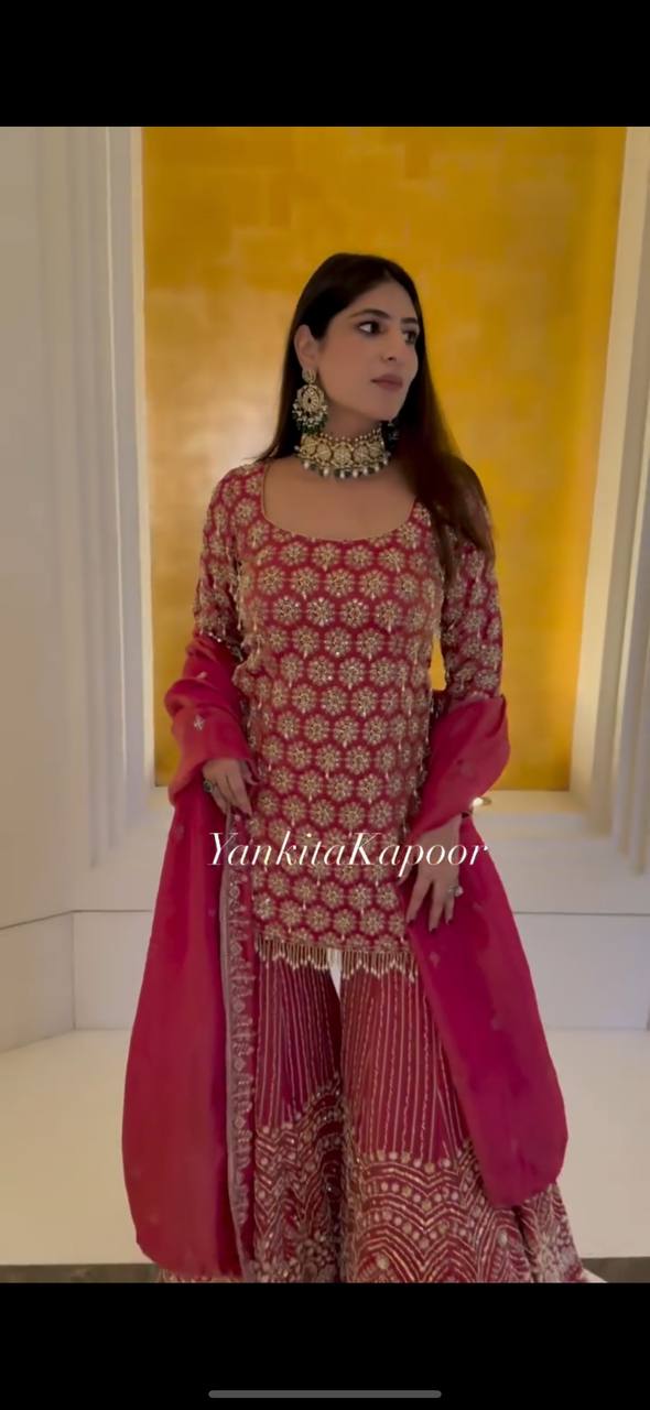 Full-body shot of a woman modeling a maroon faux georgette sharara set with intricate embroidery and sequence work, standing elegantly.