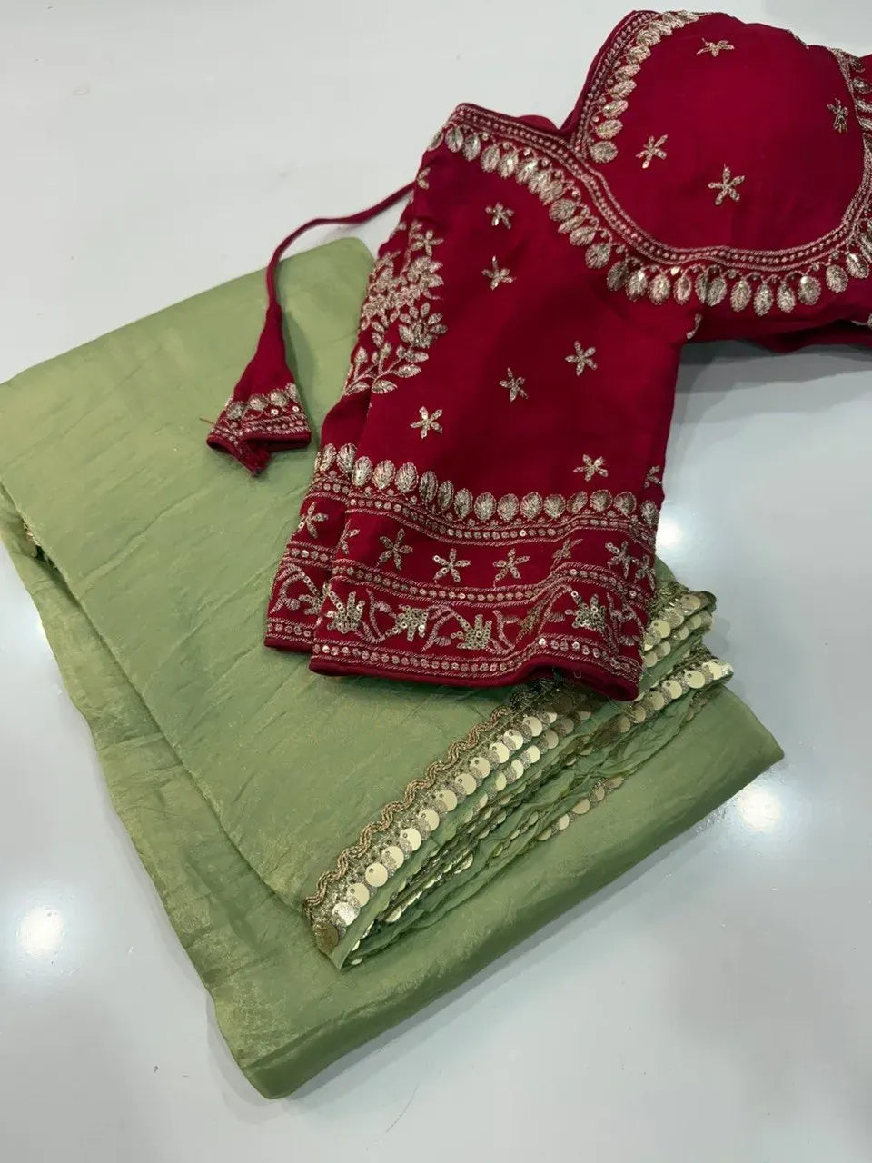 Pistachio green saree folded neatly paired with a heavy red embroidered blouse