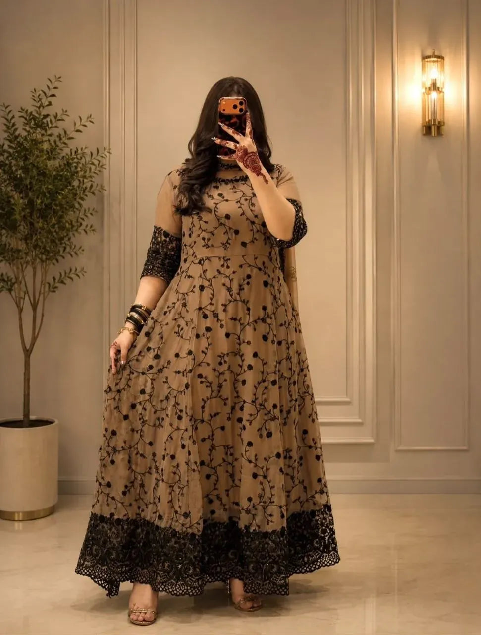 Front-facing view of a woman wearing a beige fox georgette gown with black embroidery