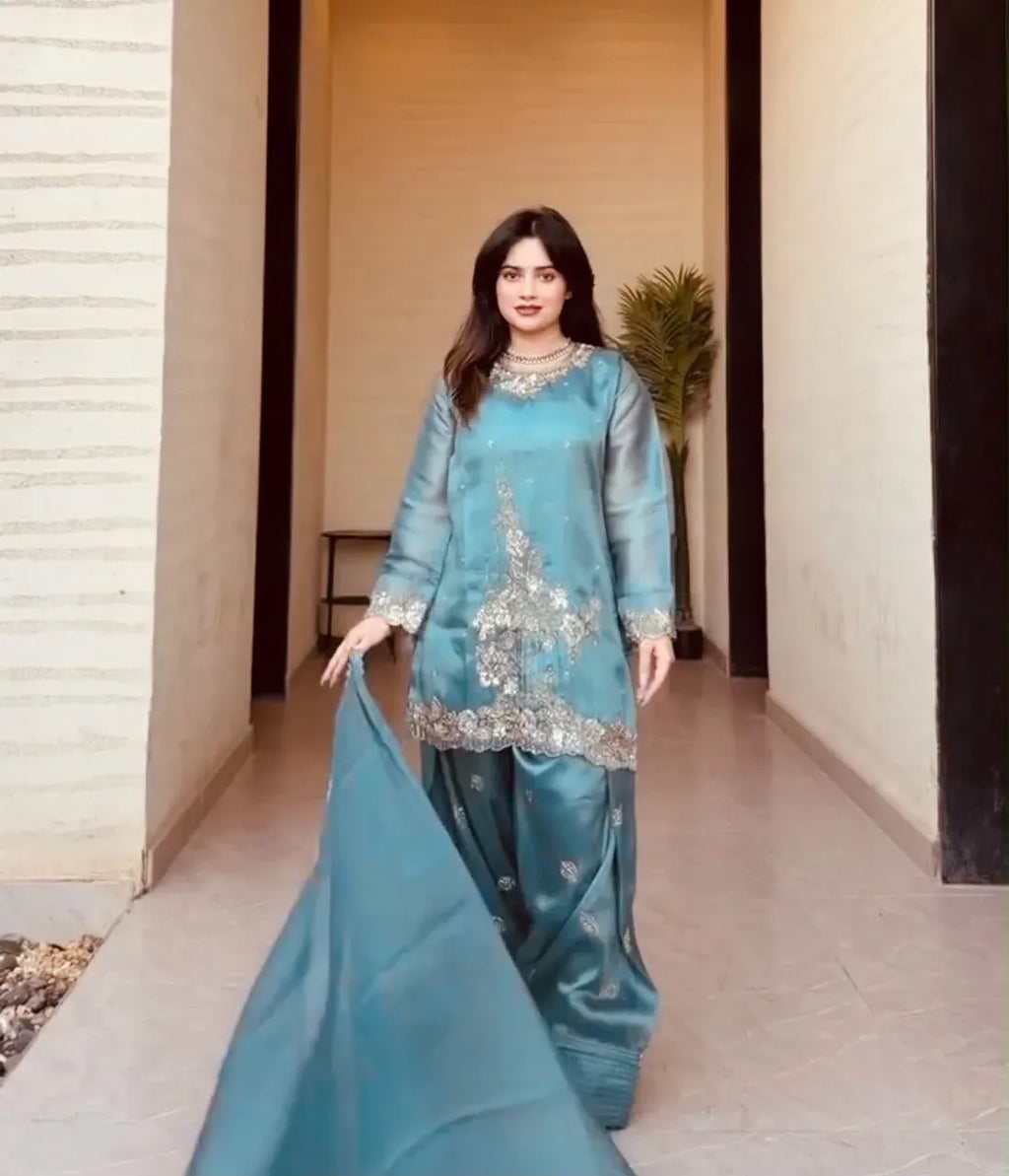 Woman wearing teal blue GMY silk suit with dupatta walking indoors