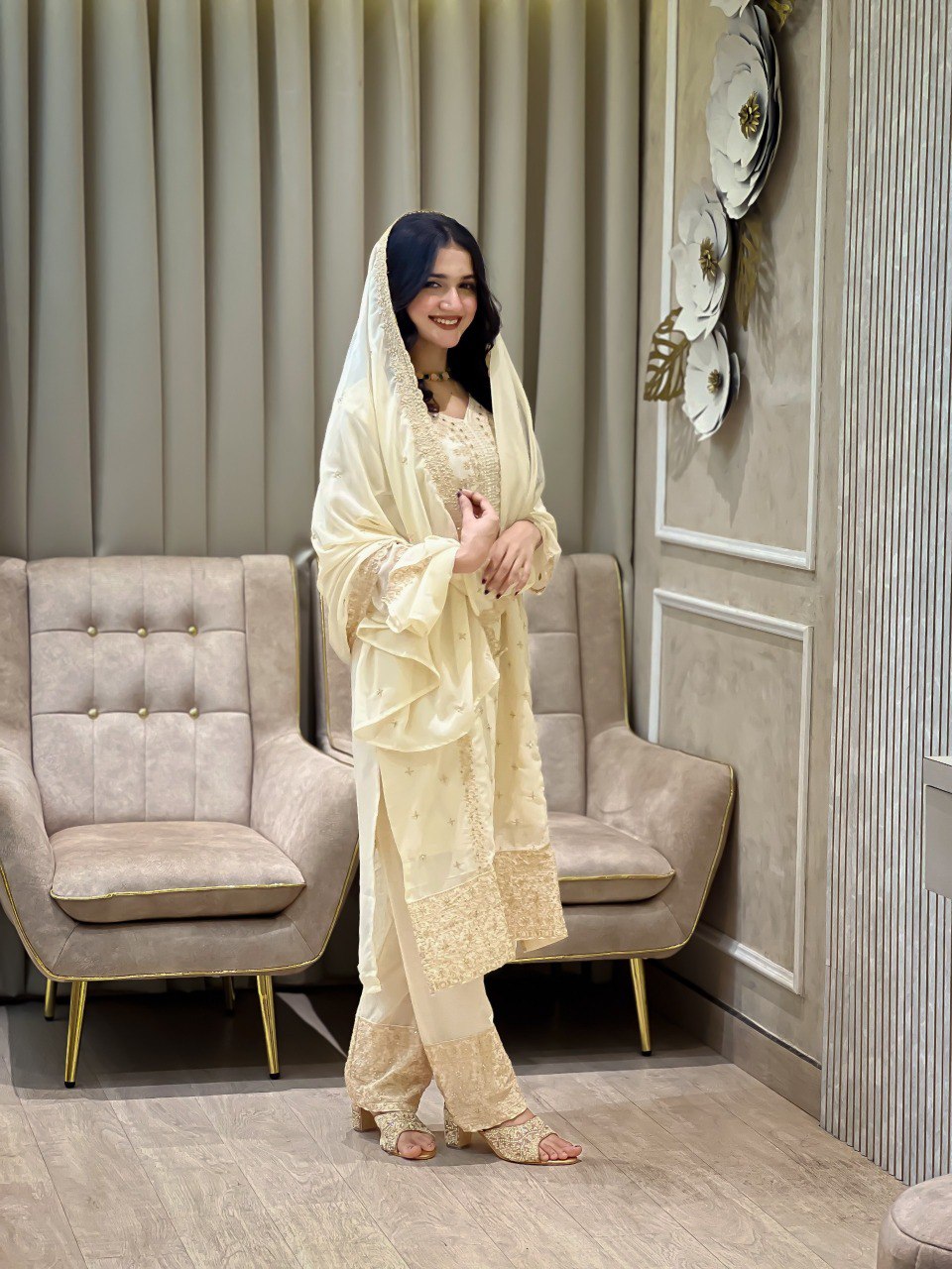 Woman posing in Cream Designer Faux Georgette Salwar Kameez Set with intricate embroidery by TRENDBUY.