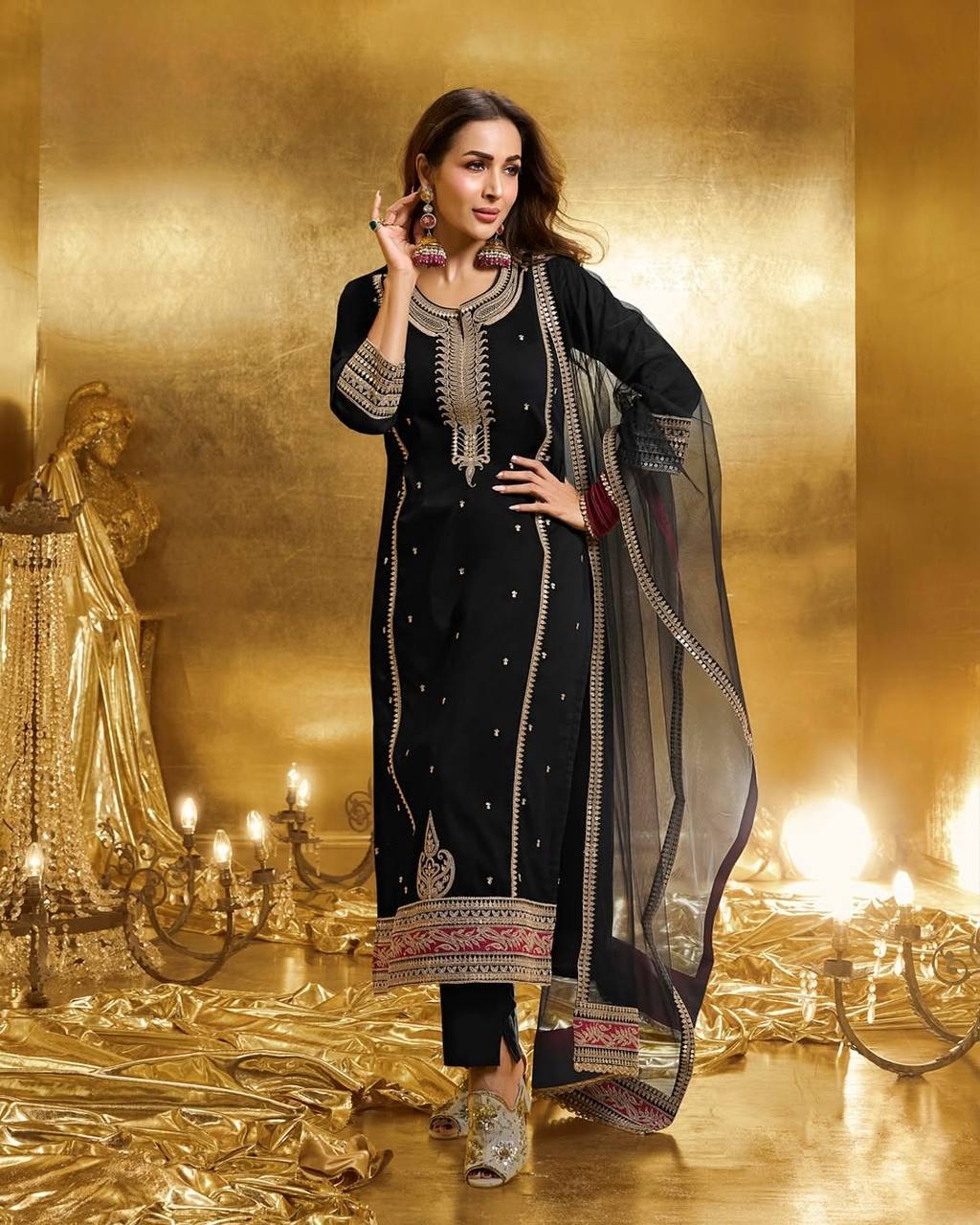 Model posing in a black designer 3 piece suit with heavy gold embroidery and red accents, perfect for party wear.