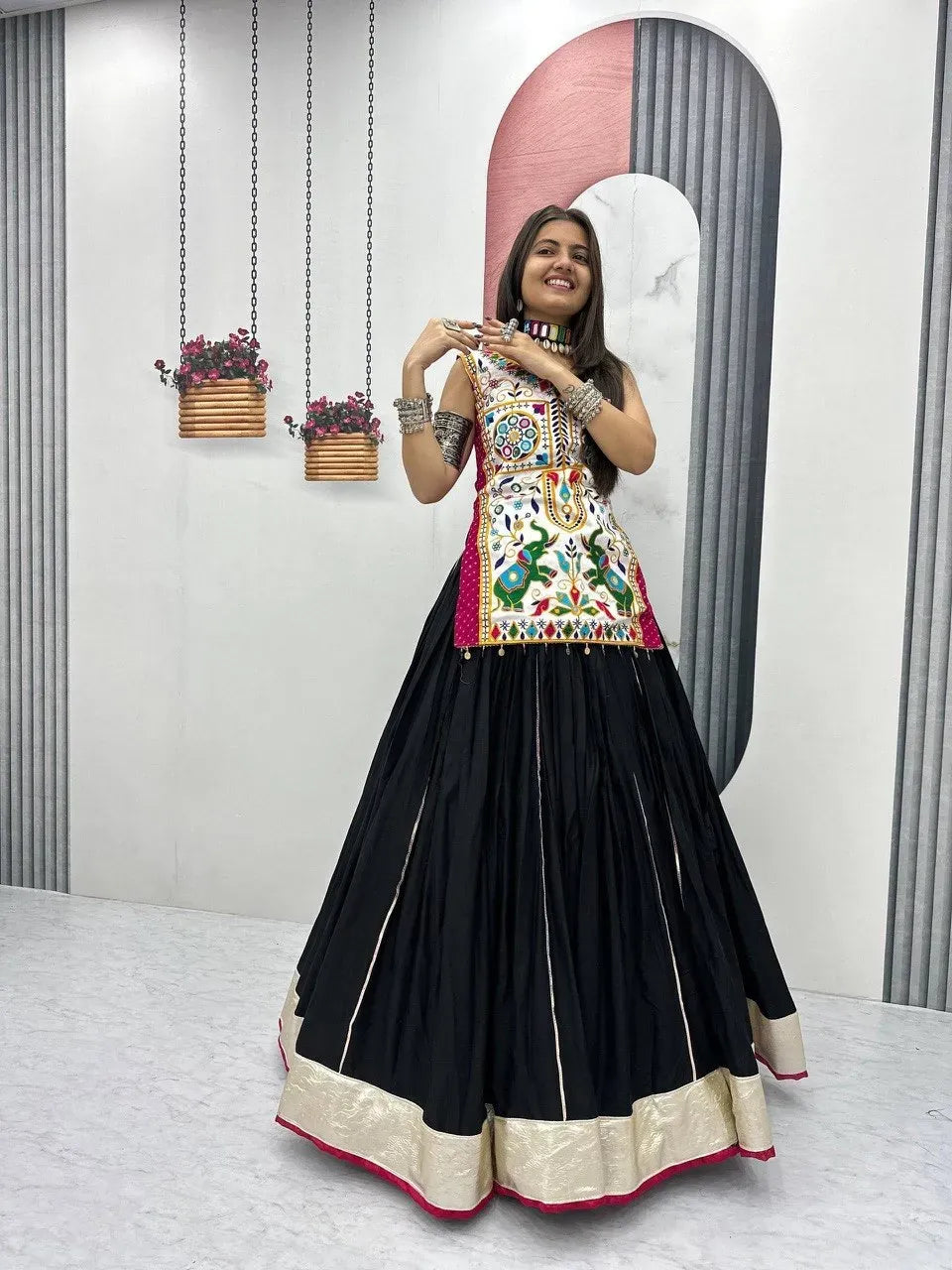 Model wearing white embroidered choli and black lehenga with mirror work