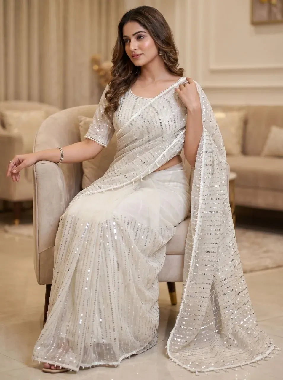 Model seated wearing elegant white net wedding saree