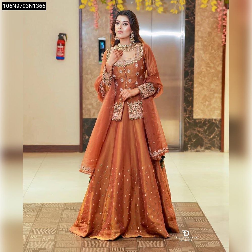 Woman wearing an elegant rust orange designer party top lehenga set, front view, looking at camera.