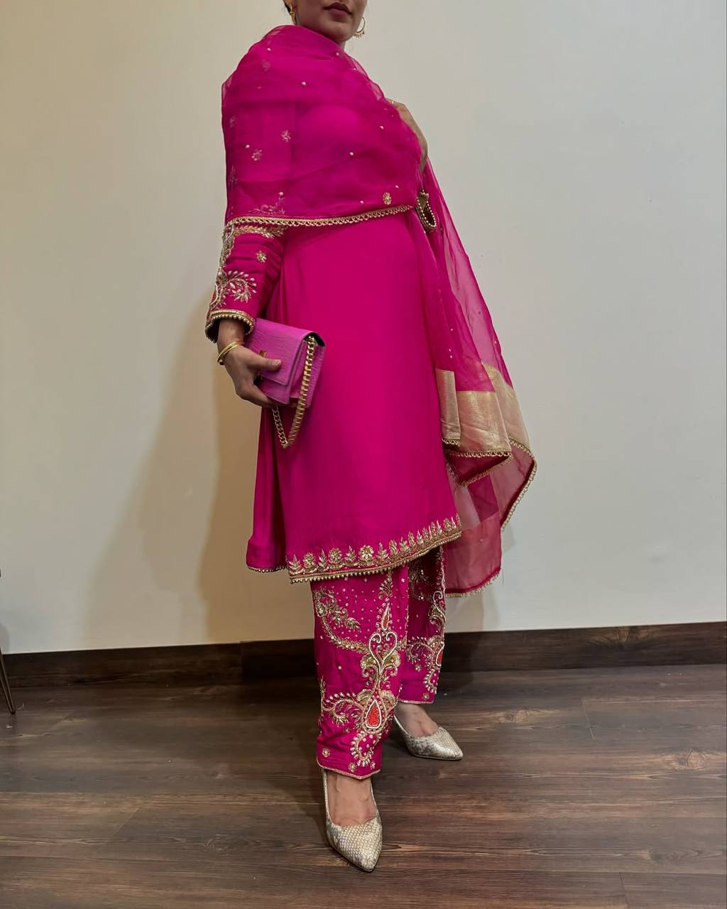 Model wearing a vibrant fuchsia Designer Party Wear 3 Piece Suit with intricate gold embroidery and pearl work, perfect for festive occasions.