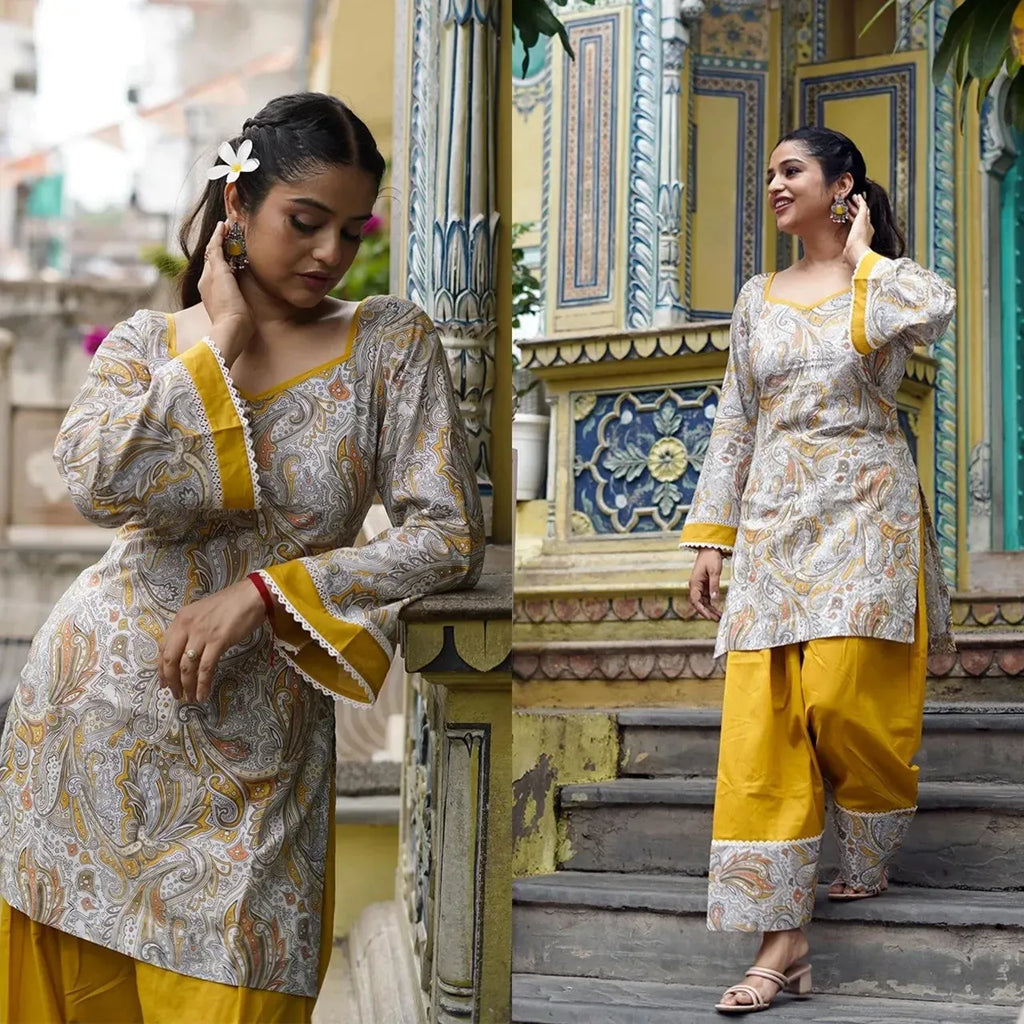 Model posing outdoors wearing printed top and yellow farshi salwar set