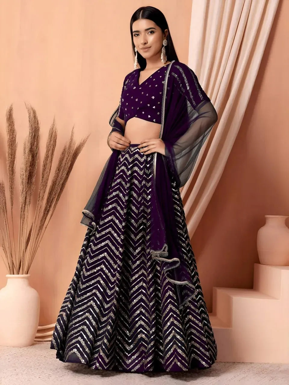 Model wearing deep purple georgette lehenga choli with gold chevron sequins and sheer dupatta