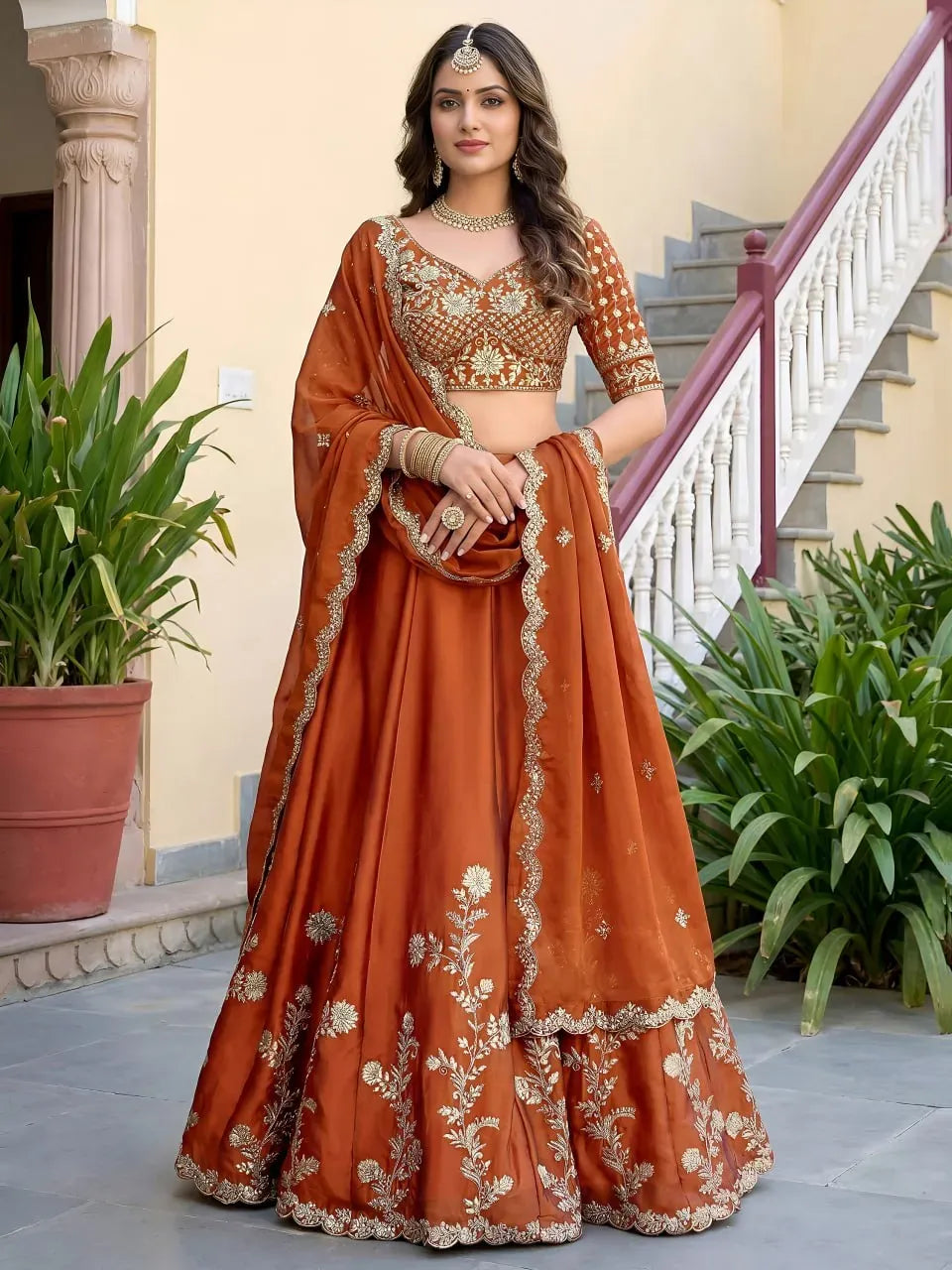 Full front view of model wearing rust orange embroidered lehenga choli with dupatta