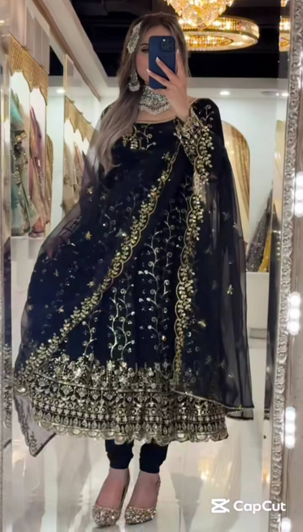 Model wearing a black designer Anarkali suit with golden sequence and embroidery work, front pose.