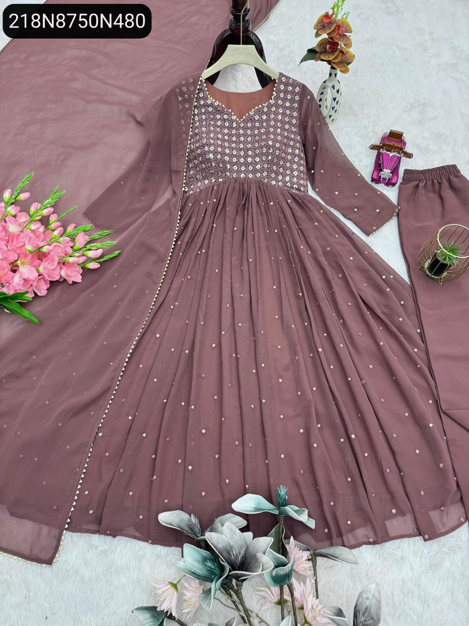 Elegant lavender sequined party wear gown set with dupatta and pants, flat lay with flowers.