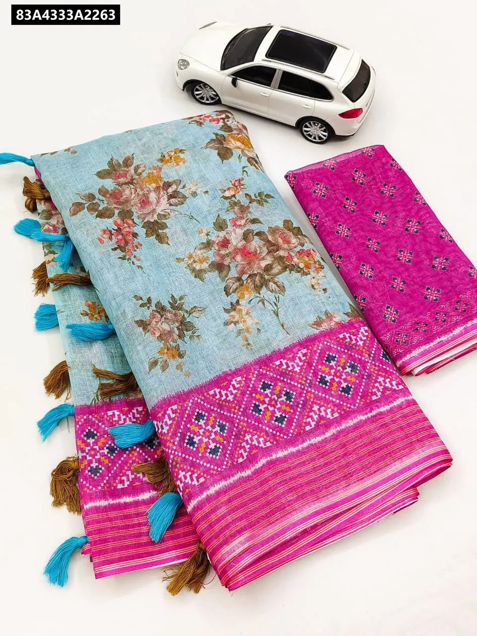 Flat lay of Sky Blue and Hot Pink Digital Print Linen Saree with floral design, ikat border, and blue tassels