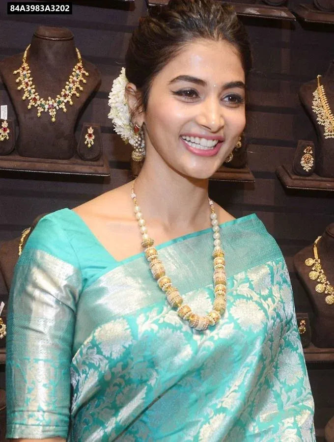 A beautiful woman smiling, elegantly draped in an Aqua Blue Lichi Silk Saree with silver jacquard weaving, wearing traditional jewelry.