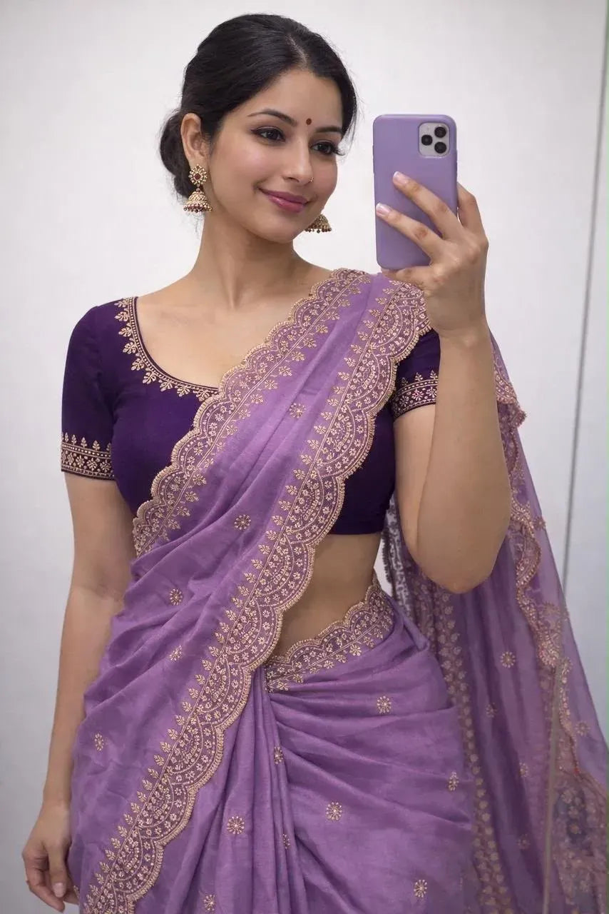 Woman in lavender georgette saree with gold embroidery holding a purple smartphone for a mirror selfie