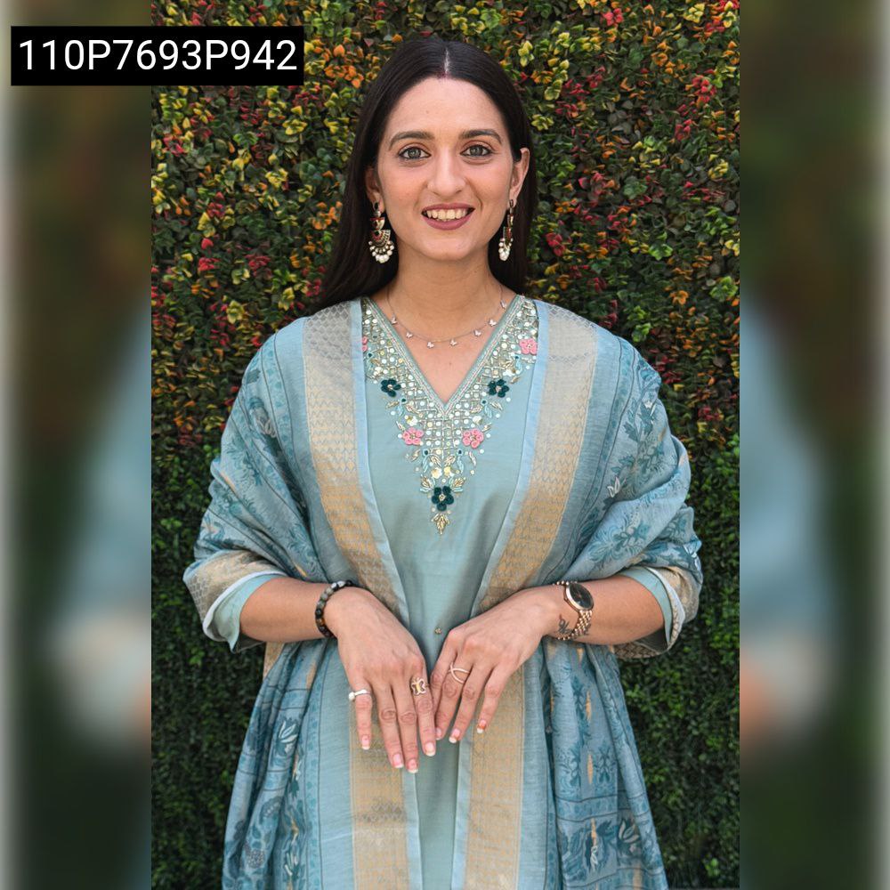 Woman smiling, wearing sea green Roman silk suit with hand embroidery and Chanderi jacquard dupatta.