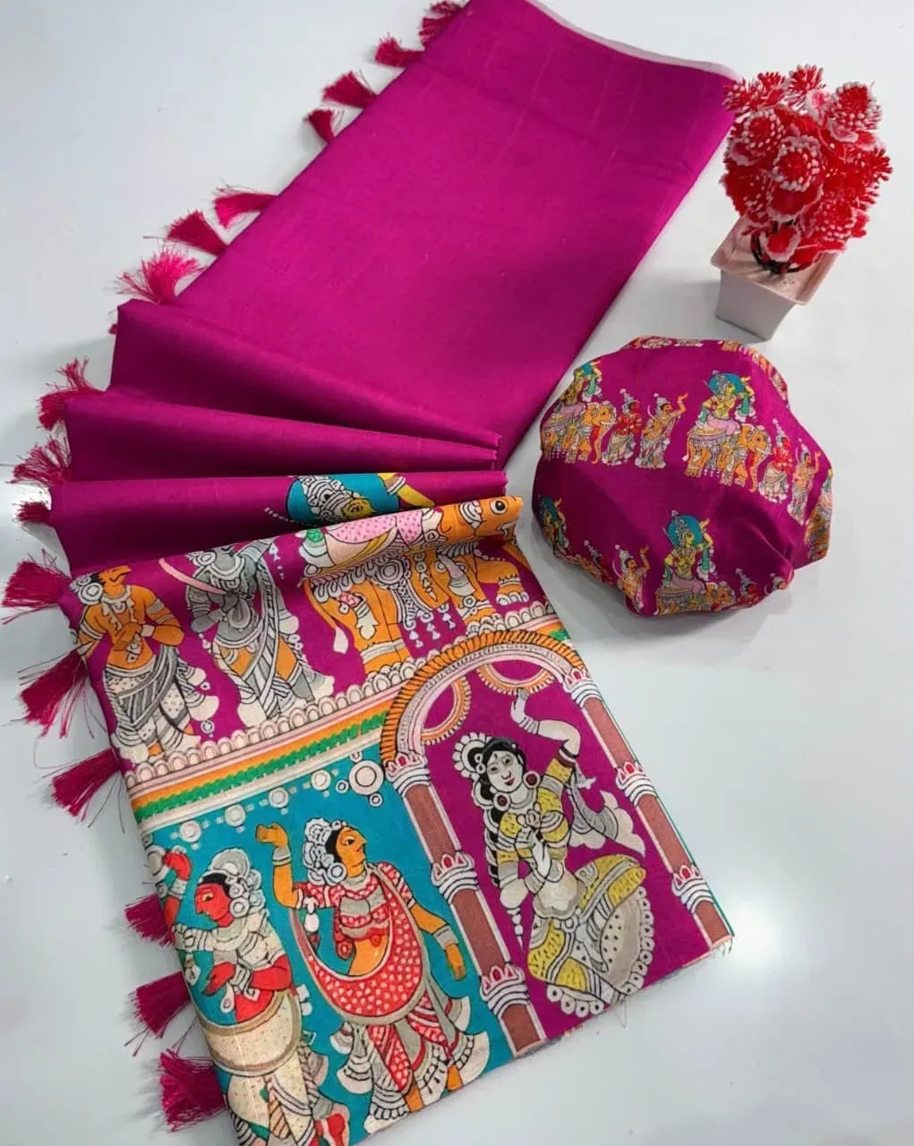 Vibrant magenta Tussar silk saree folded with matching printed blouse and decorative tassels on white background