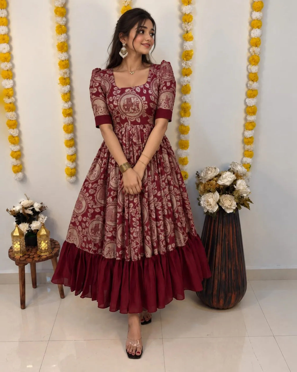 Woman posing in a maroon and cream Kalamkari print silk maxi dress with a pleated ruffle hem