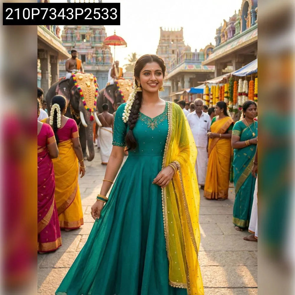 Single model in a teal Vichitra Silk Maggam work gown with a yellow sequined dupatta, smiling in an outdoor temple market.