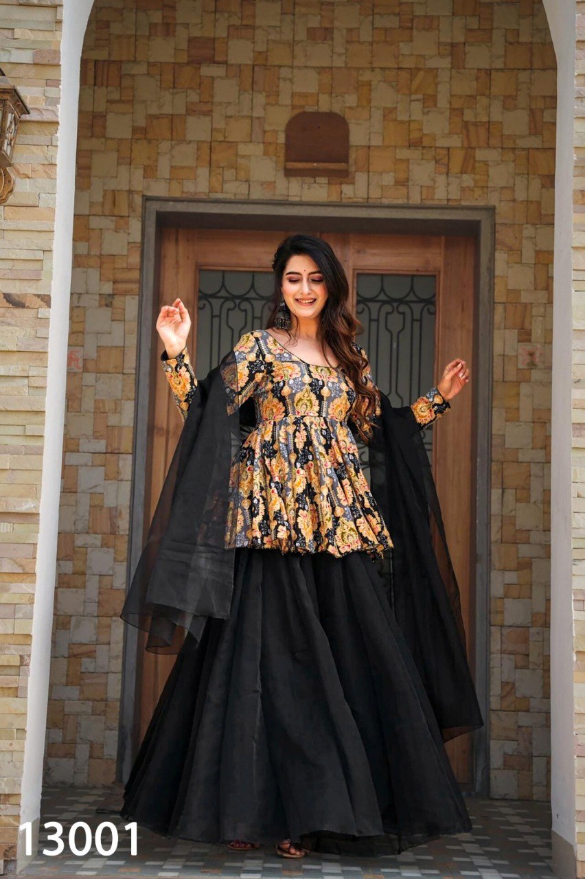 Woman posing elegantly in a black printed peplum top, black organza sharara, and matching black dupatta, full view.