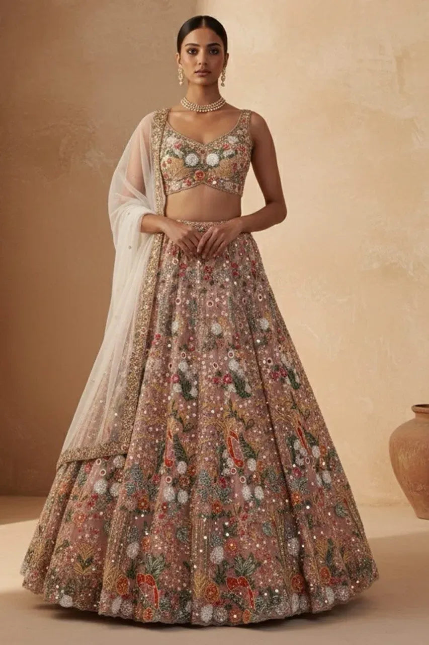 Woman posing in a peach embroidered soft net lehenga with a matching dupatta