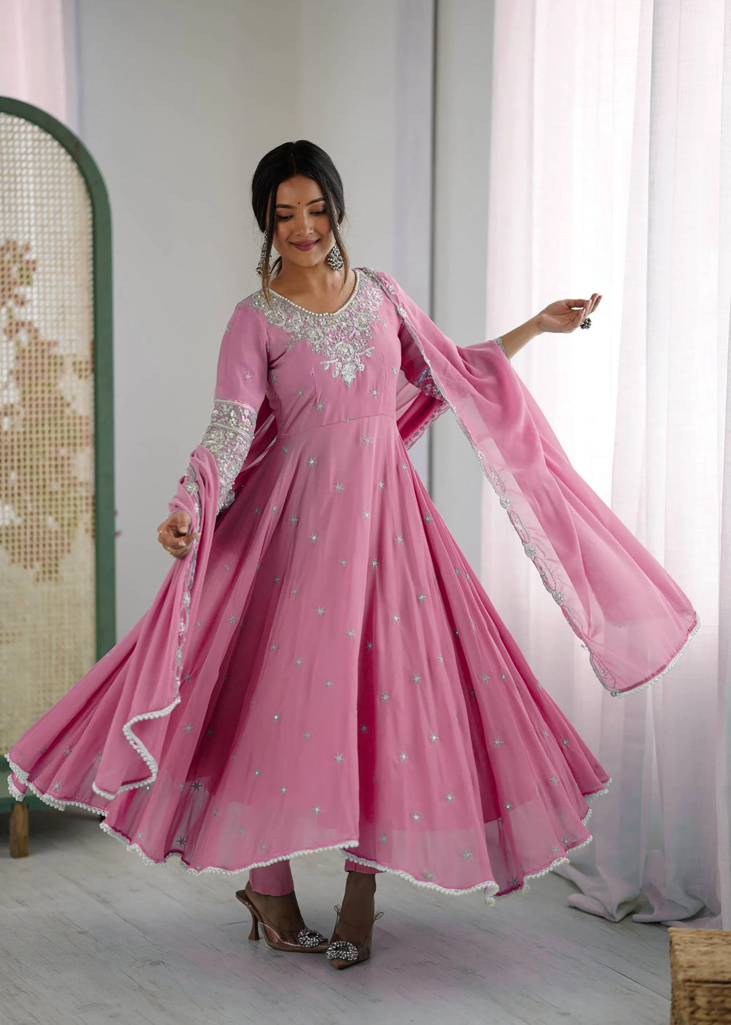 Woman posing elegantly in a light pink embroidered Anarkali Gown with full flair and dupatta.
