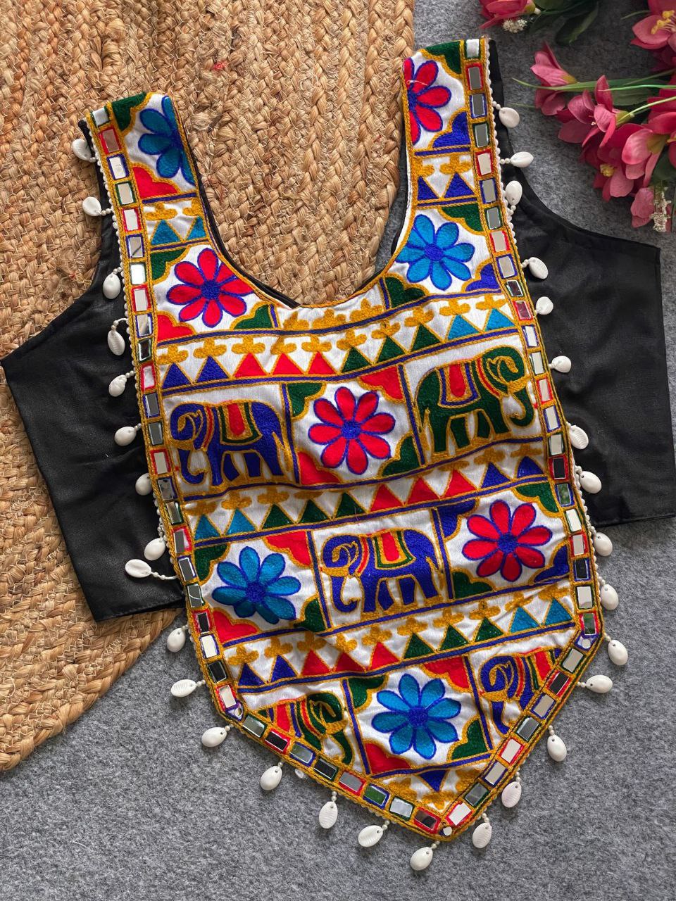 TRENDBUY Navratri special black sleeveless blouse with vibrant elephant and floral embroidery, mirror work, and cowrie shell detailing, displayed on a jute mat.