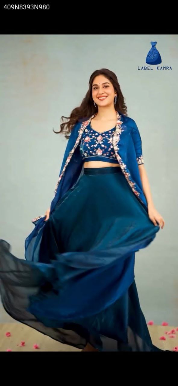 Model posing in a deep teal blue chinon embroidered bustier, flared plazo, and shrug set by TRENDBUY.