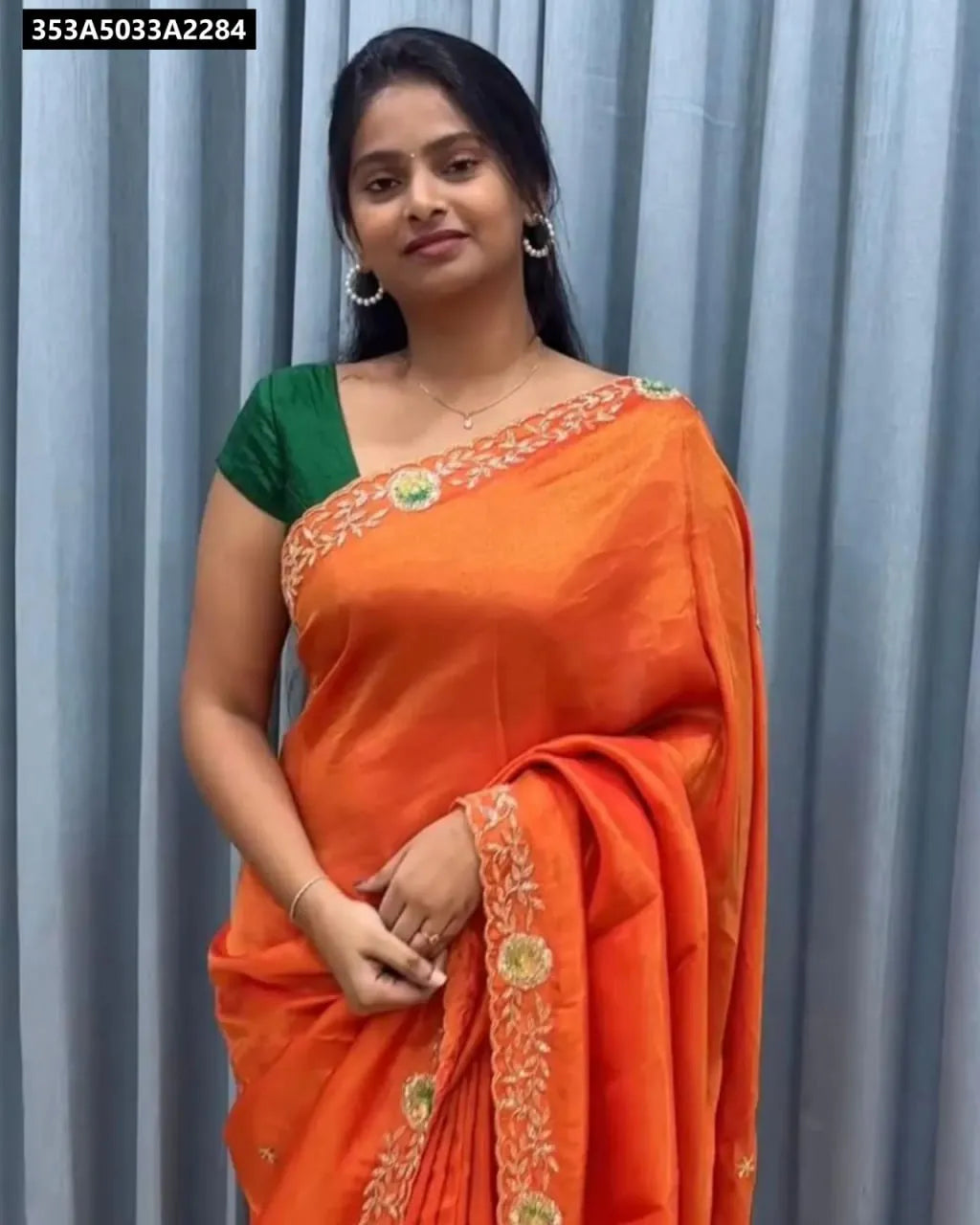 Woman wearing orange embroidered crunchy saree with green blouse, front view.