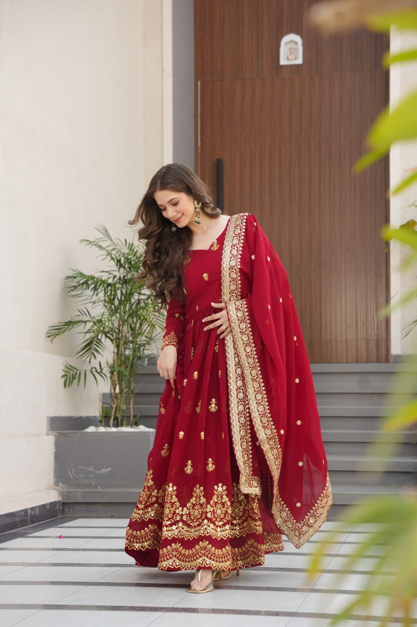 Model in maroon embroidered faux blooming Anarkali gown and dupatta, posing gracefully outdoors.