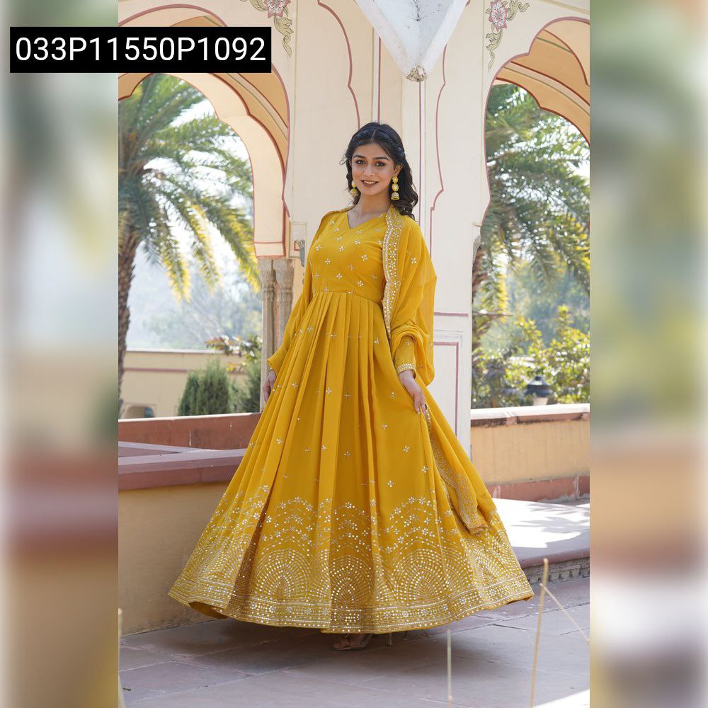 Full body shot of a smiling model posing in a vibrant mustard yellow embroidered georgette anarkali gown with a matching dupatta.