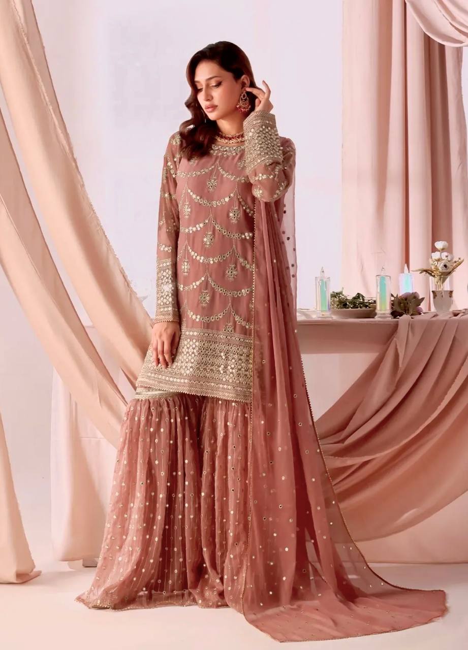 Woman posing elegantly in a Peach Rust embroidered faux georgette kurta sharara set with dupatta, showcasing the intricate sequence work.