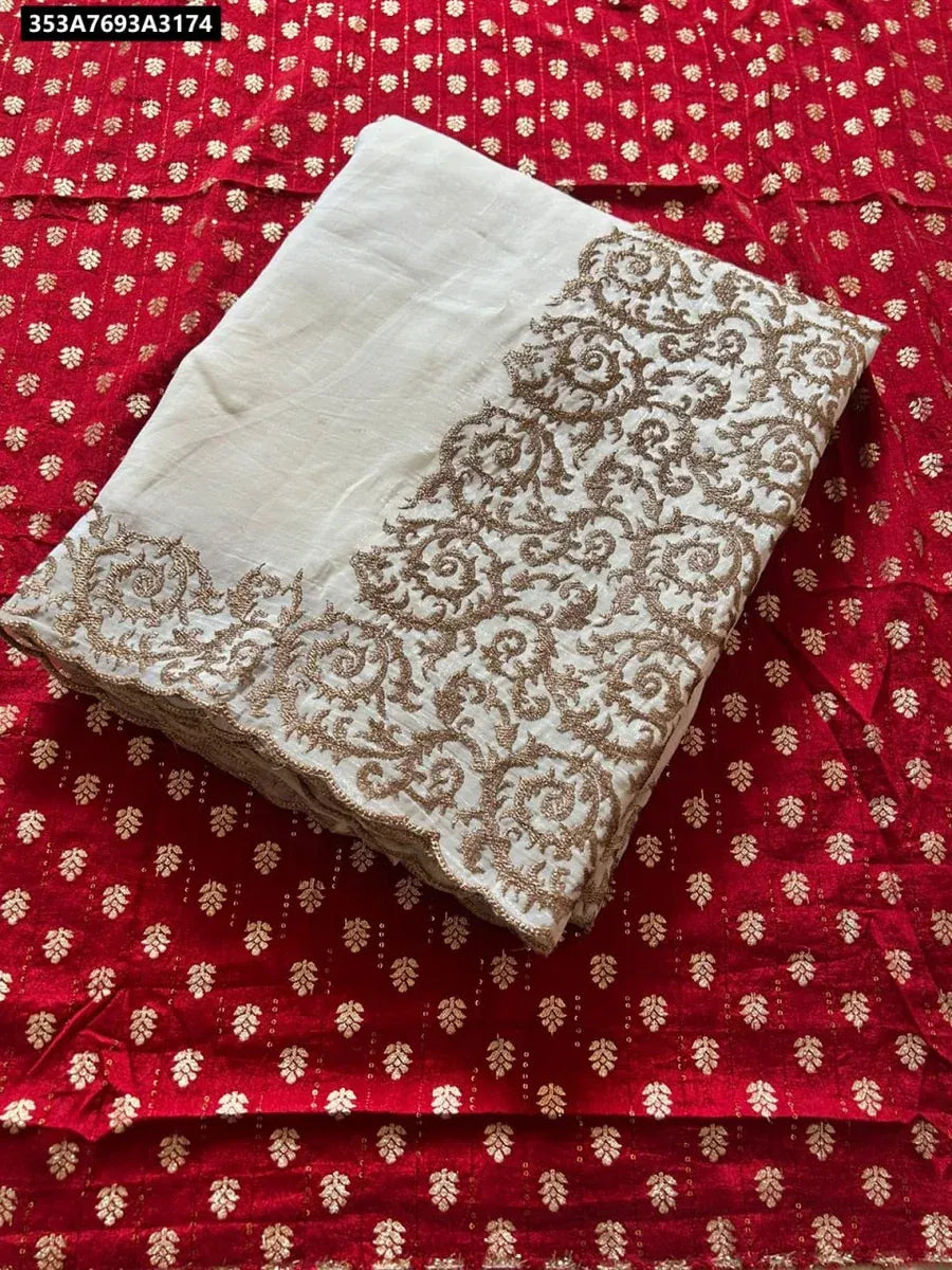 Folded white embroidered silk crush saree on a red patterned background, showcasing the cut-work border.