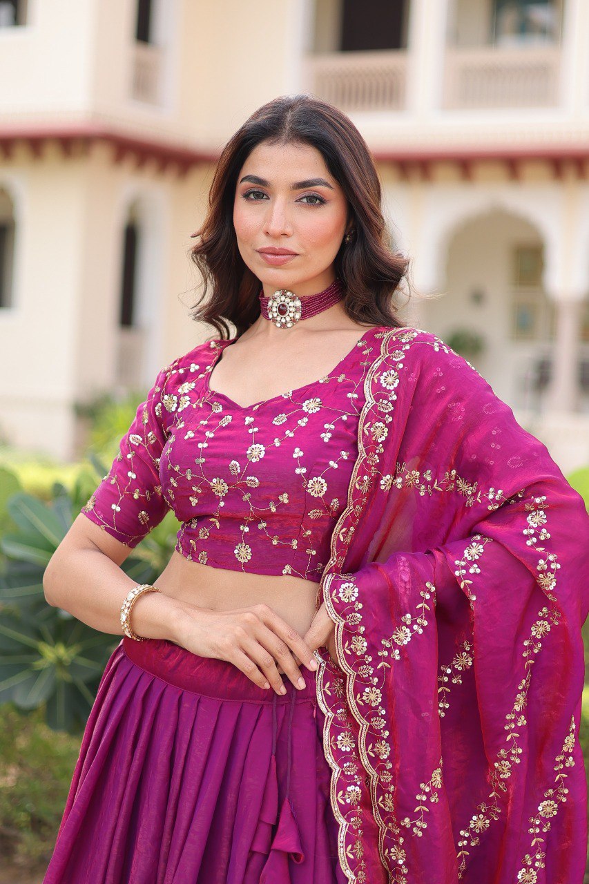 Model showcasing intricately embroidered blouse and pleated lehenga in magenta.