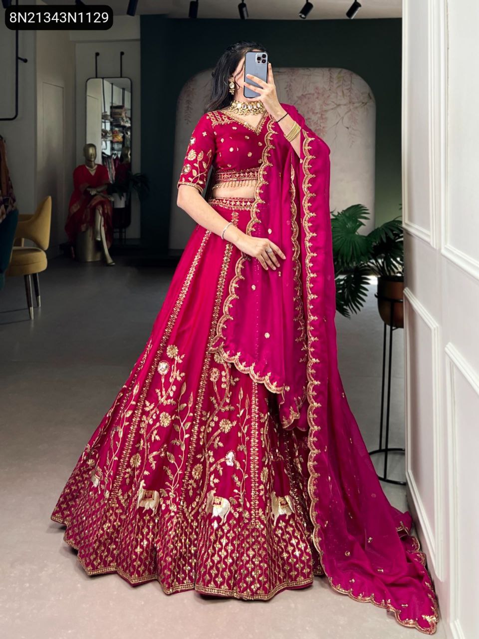 TRENDBUY Fuchsia Pink embroidered silk lehenga with golden work, front view on model holding phone
