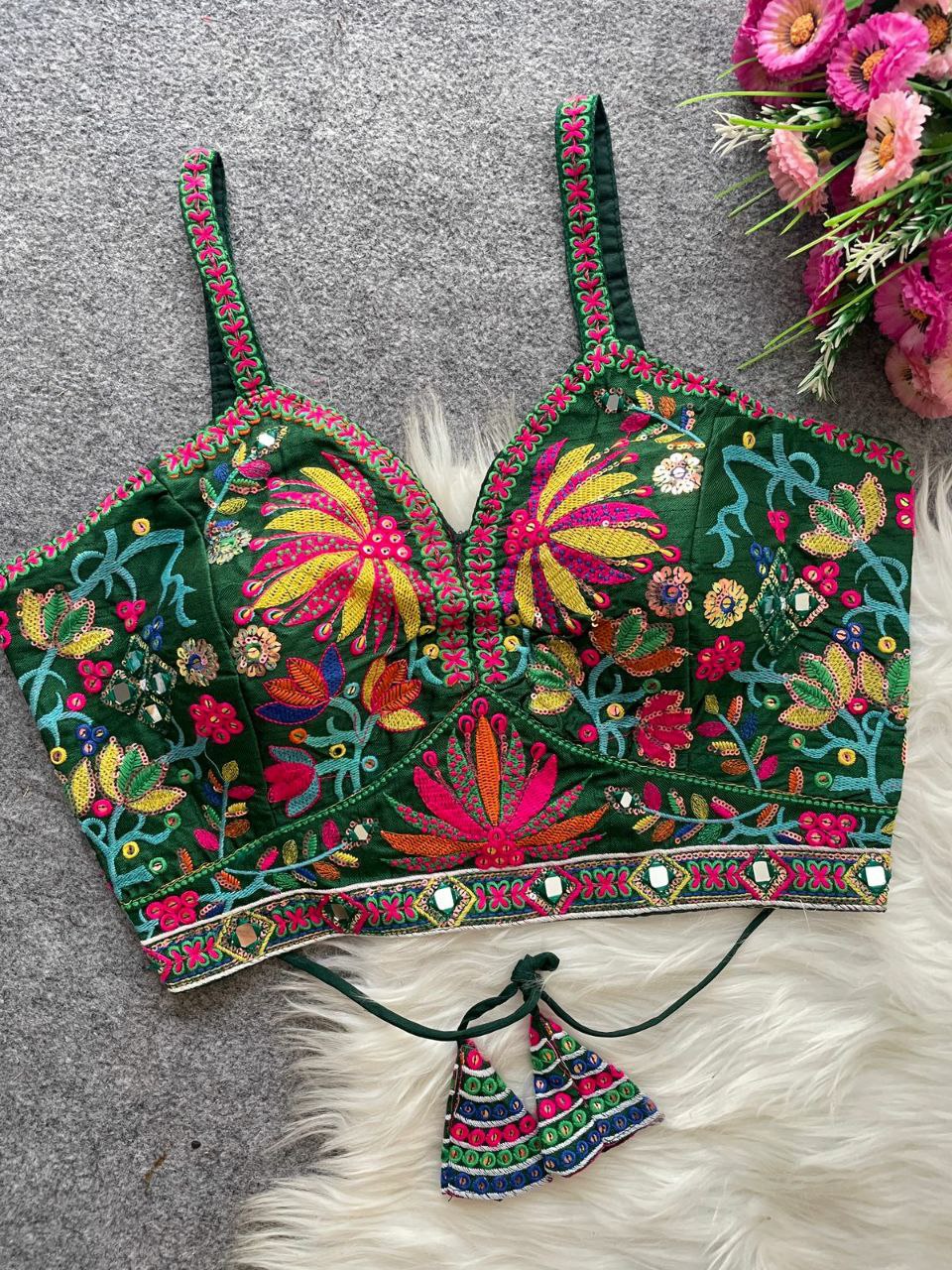 Green sleeveless blouse with colorful floral embroidery, sequence, and mirror work, front view.