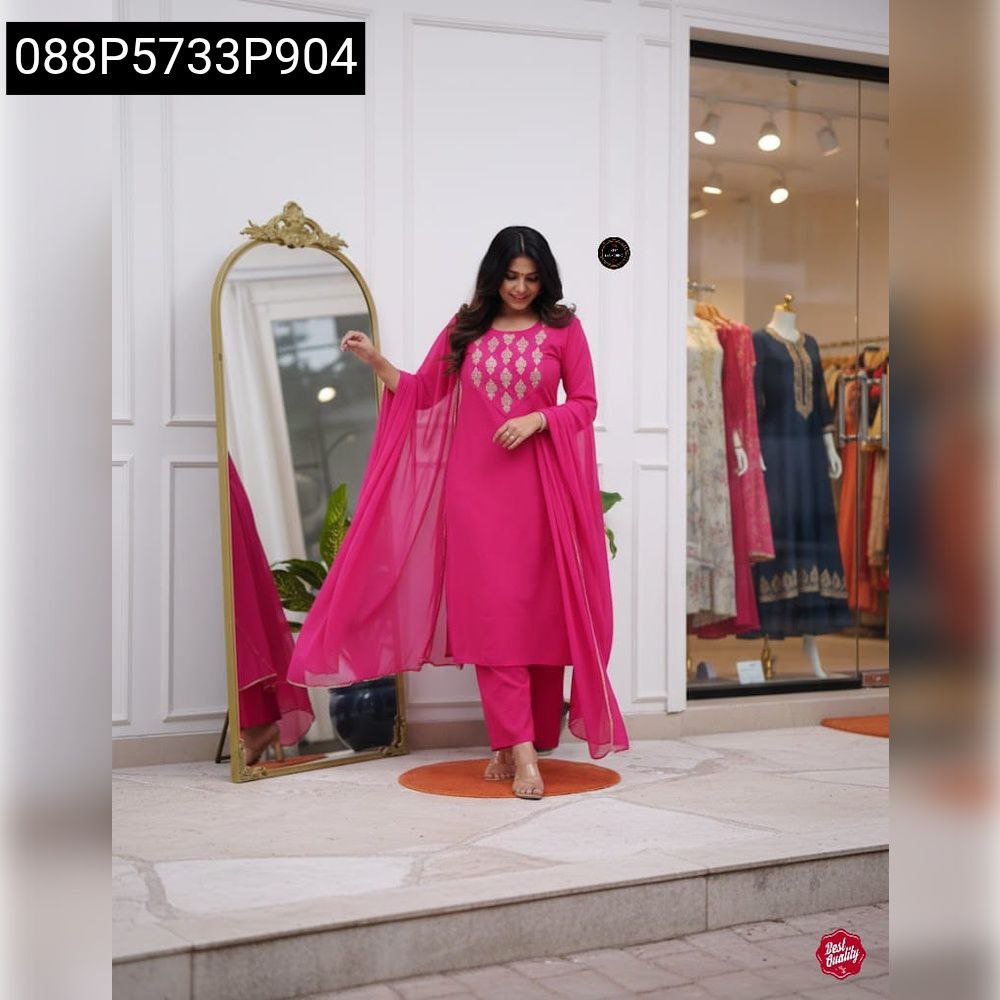 Full body shot of model posing in a vibrant fuchsia embroidered kurti set with a flowing dupatta, in front of a mirror in a stylish boutique.