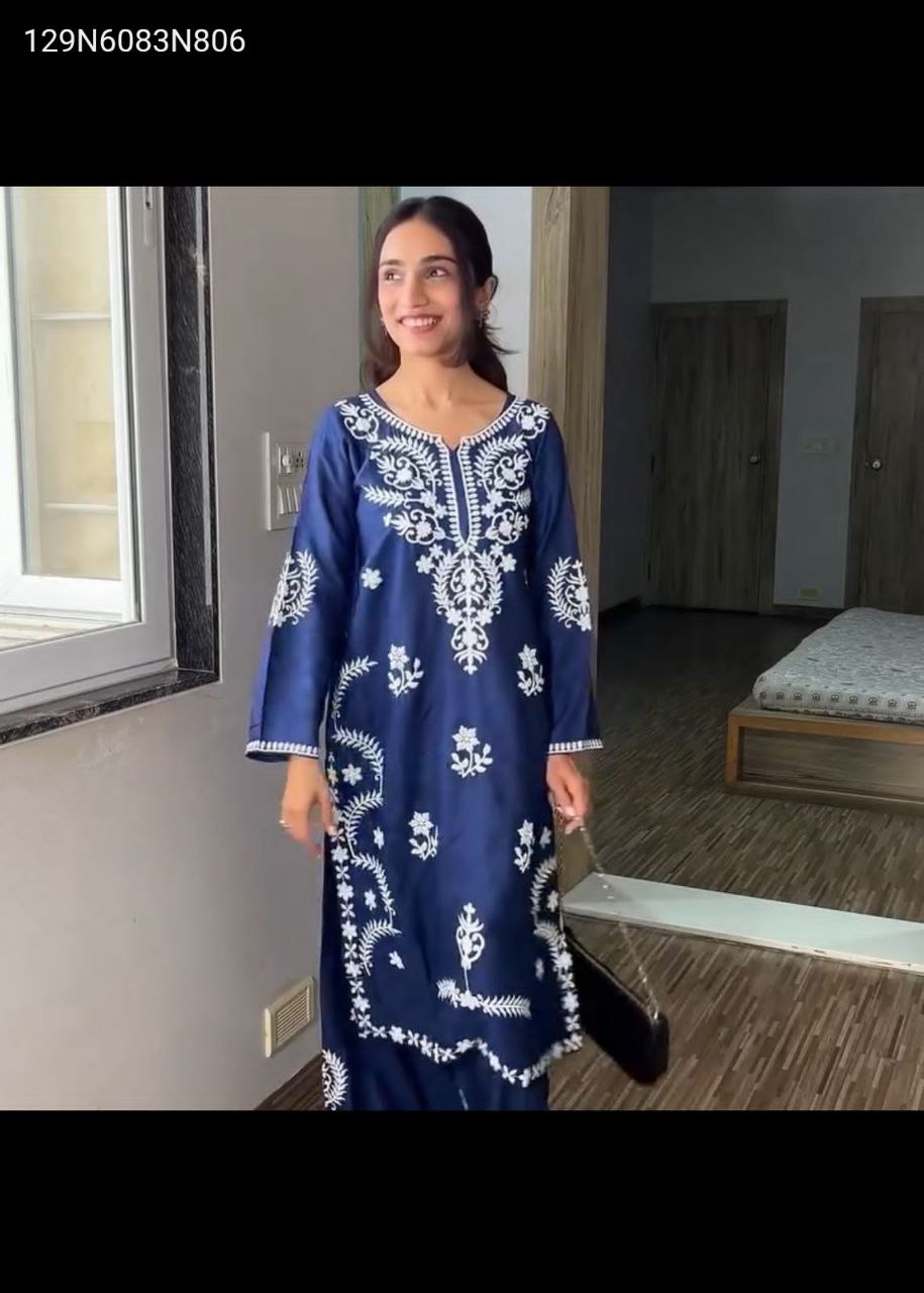 Woman posing in embroidered navy blue rayon kurta with white embroidery and matching plazzo pants.