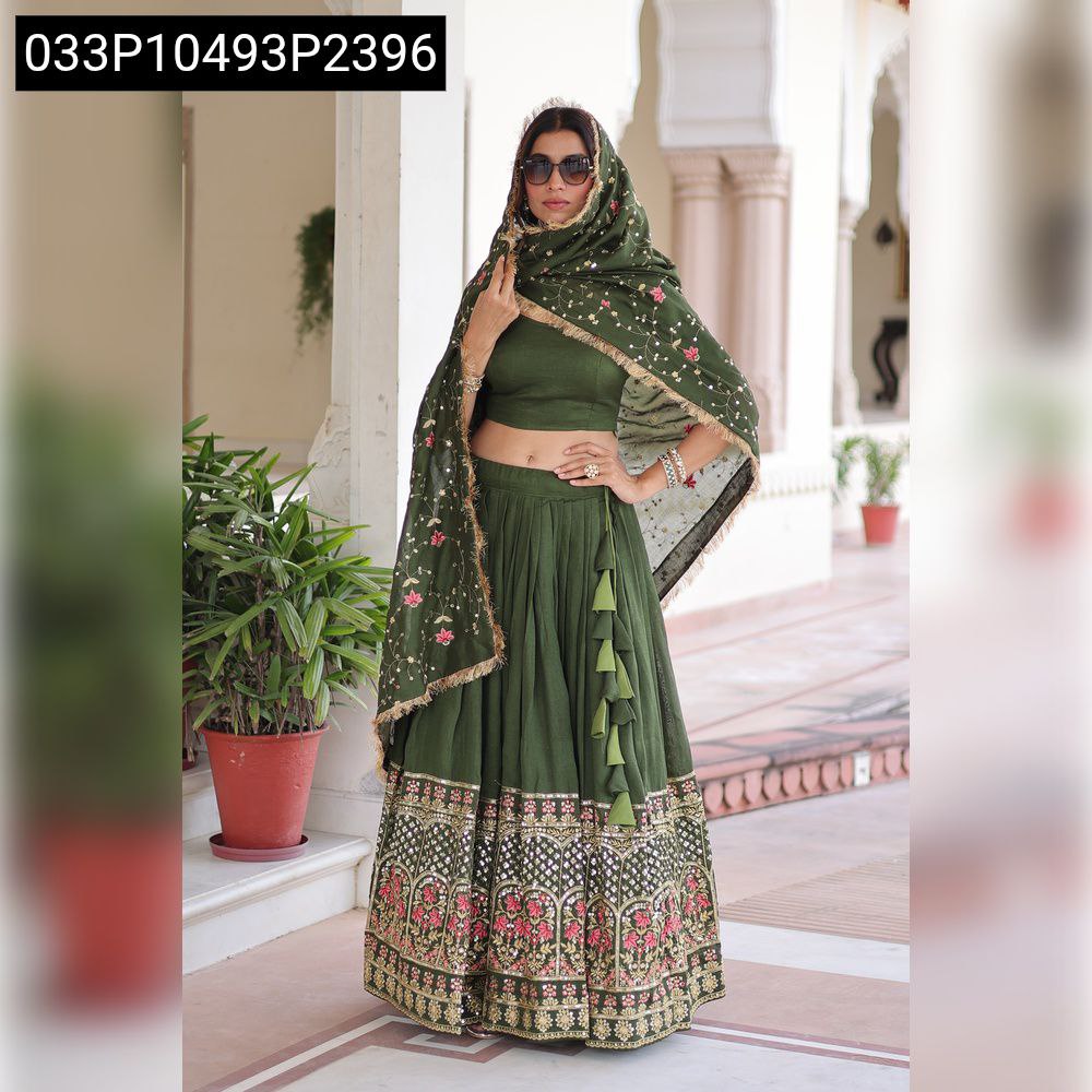 A woman in a full-stitched olive green Vichitra Silk lehenga with heavy sequin and thread embroidery, a matching blouse, and an embroidered dupatta, standing front-facing.