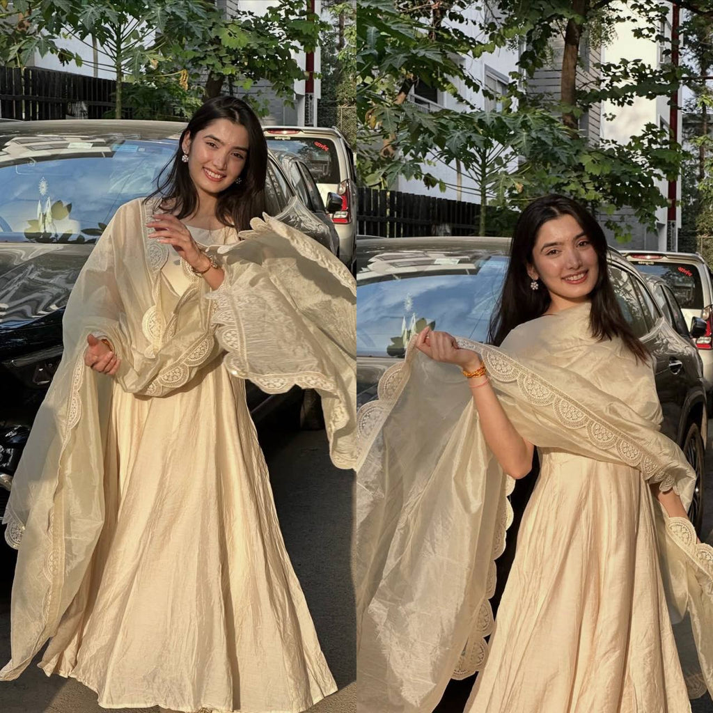 Model in full Cream Anarkali gown, smiling, posing by a black car.