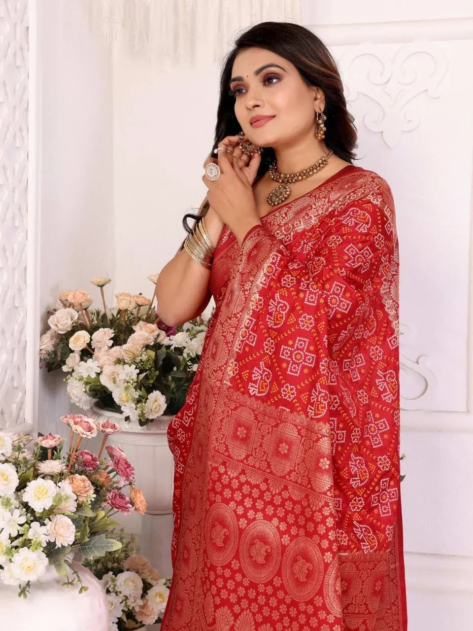 Close-up of model wearing red bandhej print saree with traditional jewelry