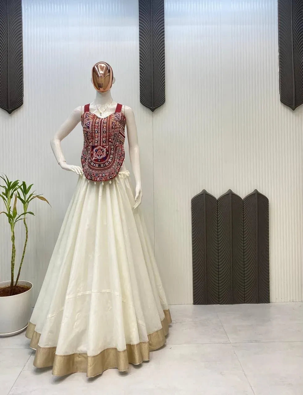 Full-length front view of cream cotton lehenga with gold border and red embroidered blouse on a mannequin