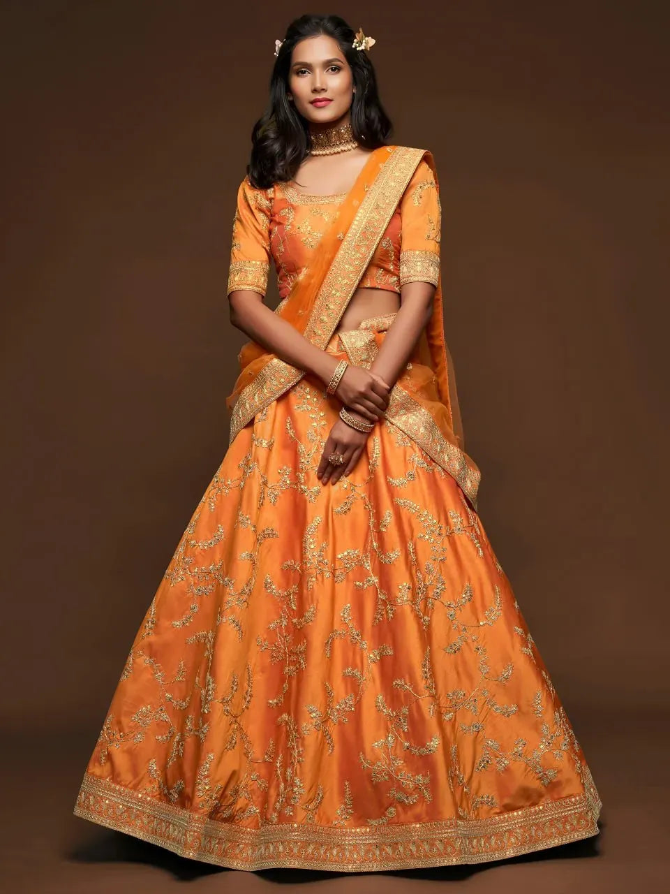 Front facing model wearing orange embroidered designer lehenga choli with dupatta